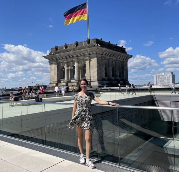 A young female in front of a building with the German flag.